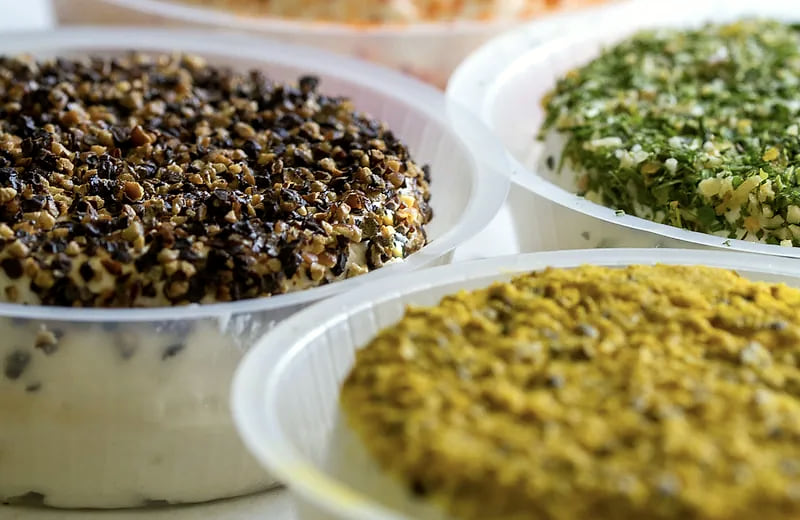 Des fromages roulés au poivre, aux herbes et au piment, serrés les uns contre les autres