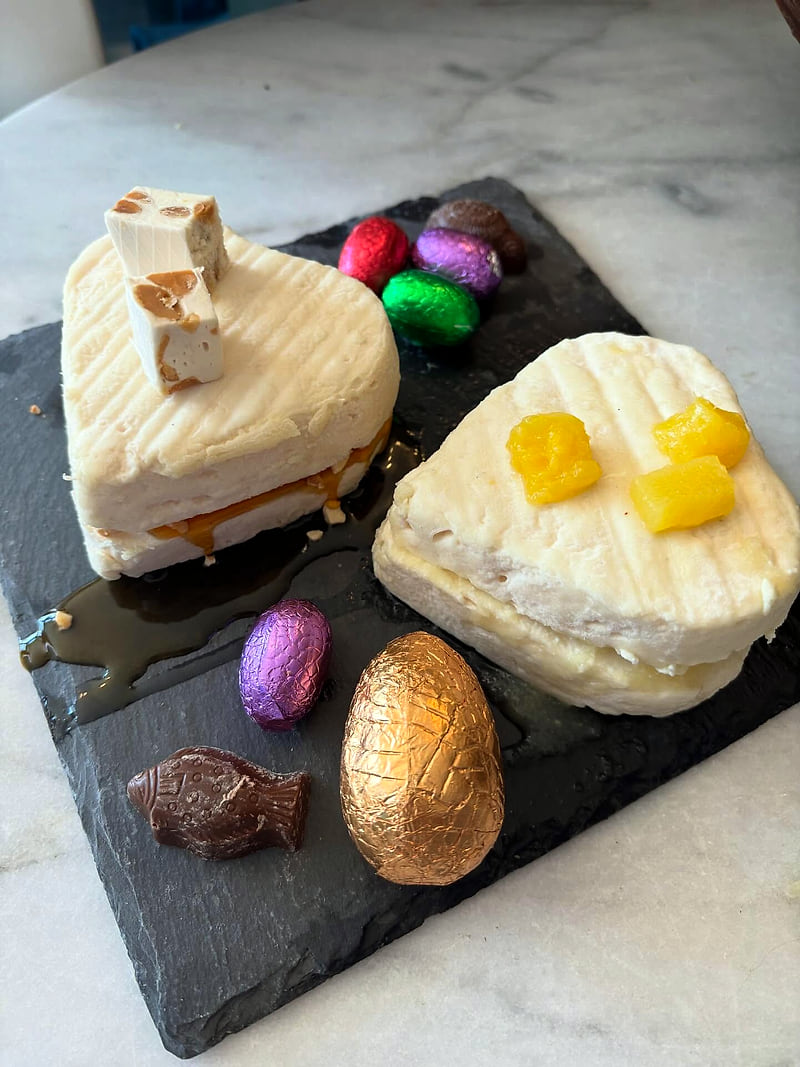 Deux fromages en forme de cœur décorés pour Pâques, sur une ardoise avec des œufs en chocolat