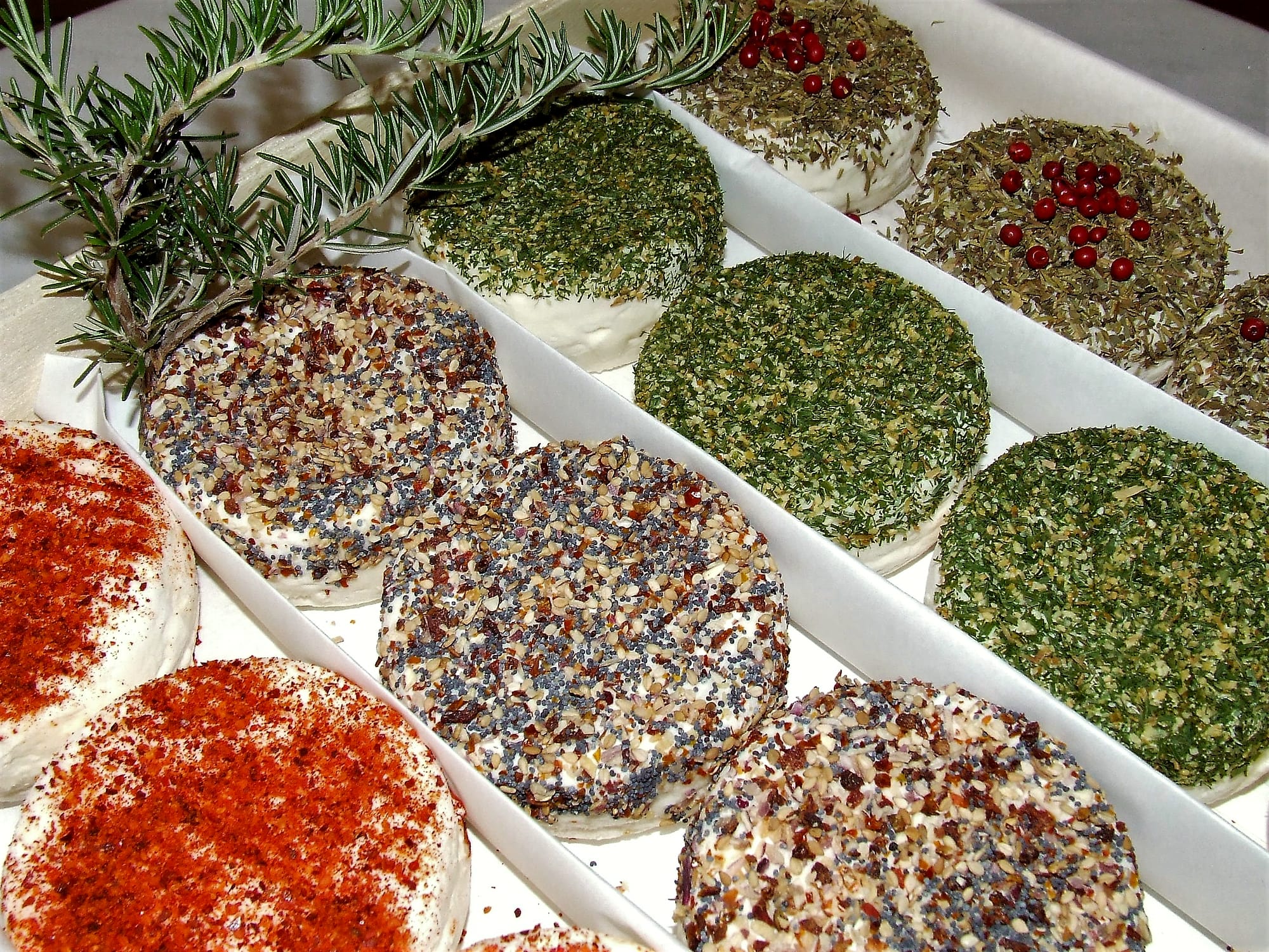 Des fromages de chèvre enrobés de poivre, de fines herbes et de piment, alignés sur un plateau
