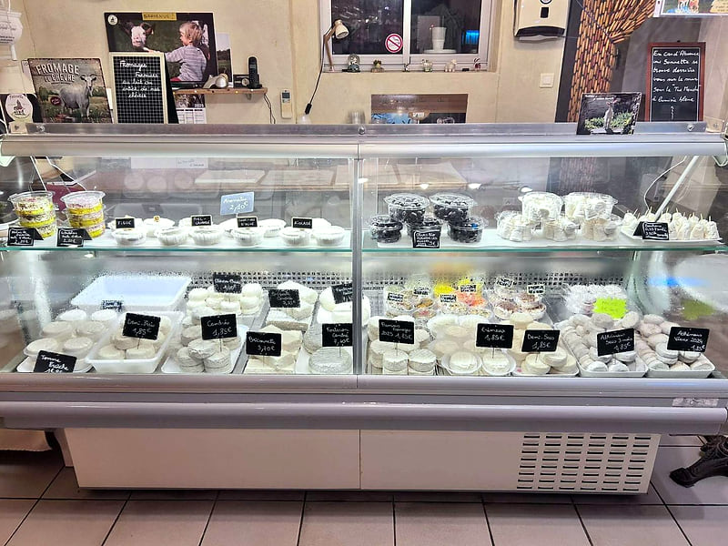 La vitrine réfrigérée du magasin, garnie de fromages de chèvre étiquetés sur ardoise